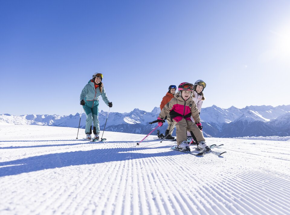 A family with kids skiing together on a sunny day.