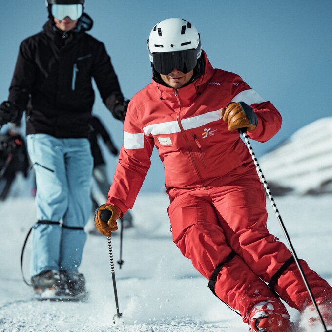 A group of skiers in the snow. The skier in red is leading.