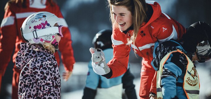 Een ski-instructeur laat een kind een speelgoed zien tijdens de les.