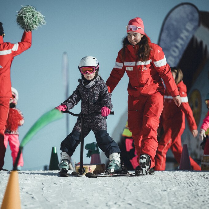 A girl is learning to ski with an instructor in the snow.