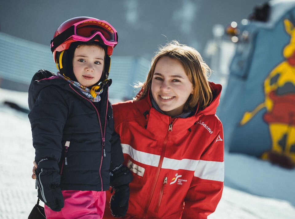 A ski instructor poses with a young skier in the winter season.