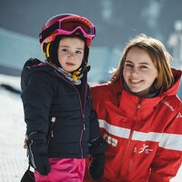 Eine Skilehrerin steht mit einem kleinen Skifahrer in der Wintersaison.