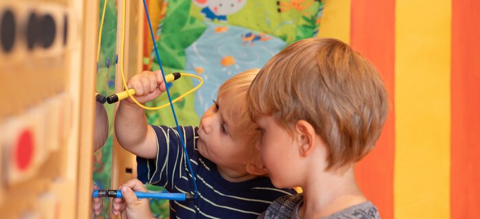 Two children creatively using pens on a play board.