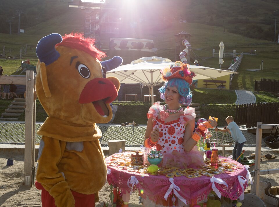 Ein Clown und ein Maskottchen interagieren unter Sonnenschein.