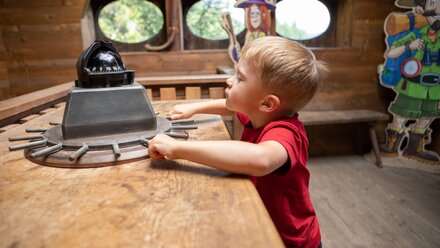A boy explores the helm on a pirate ship.