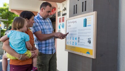 Family reading information about the village tour in Ladis.