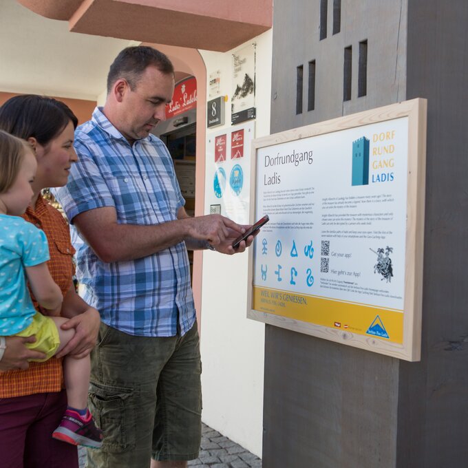 Familie liest Informationen zu Dorf Rundgang in Ladis.