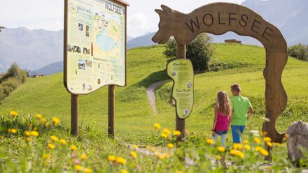 Children at the sign of Wolfsee in the green.