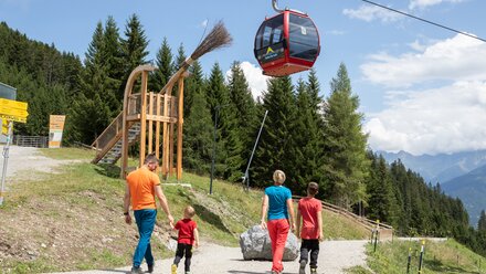 A family walks a path towards a cable car to enjoy the mountains.