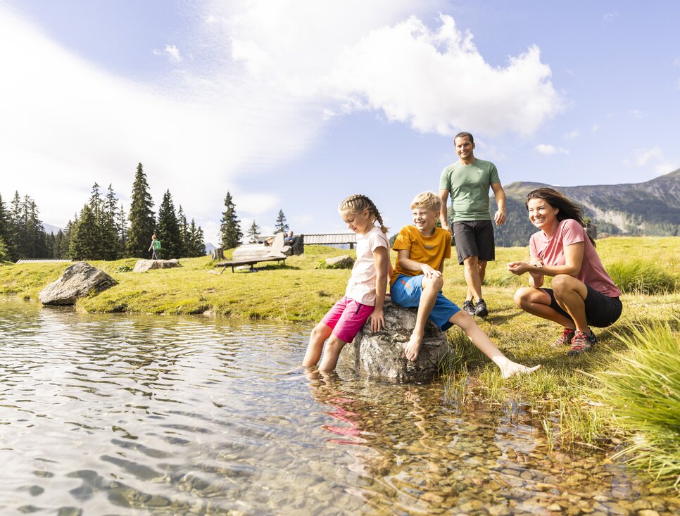 Vier Personen genießen einen Tag am See, spielen und lächeln.