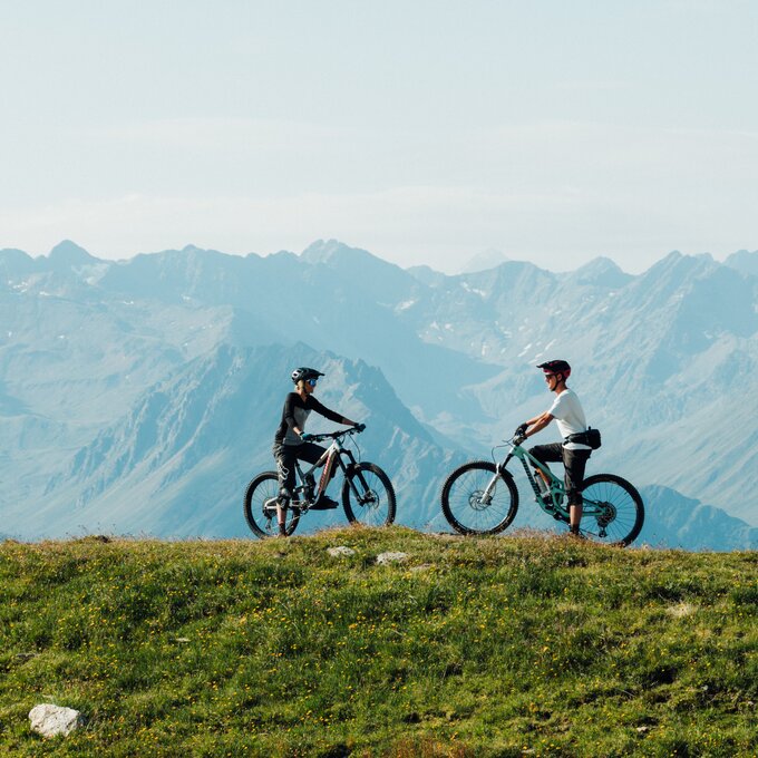 Zwei Radfahrer genießen die Aussicht in den Bergen.
