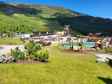 Ein belebter Freizeitbereich mit Spielplatz und Bergblick.