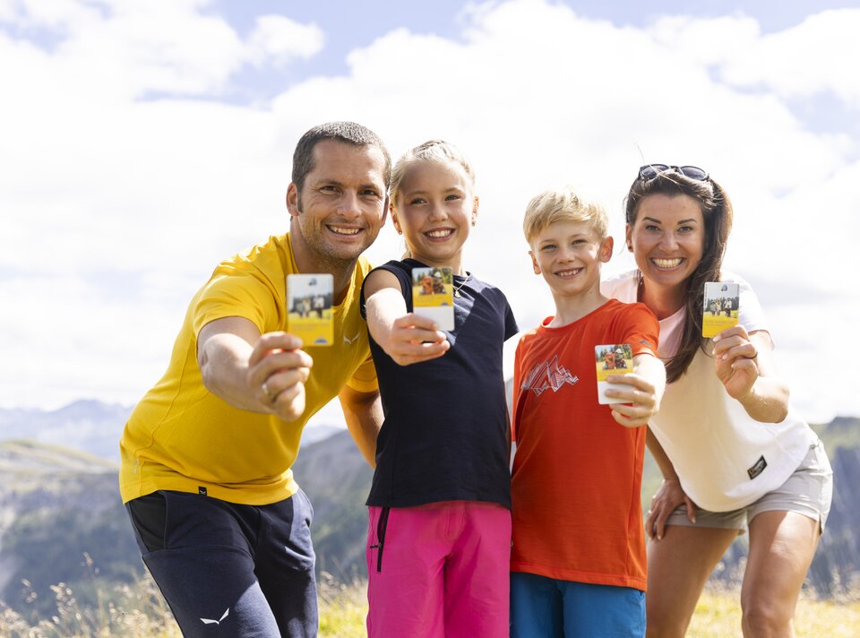 Een gelukkige familie poseert buiten met kaarten in hun handen.