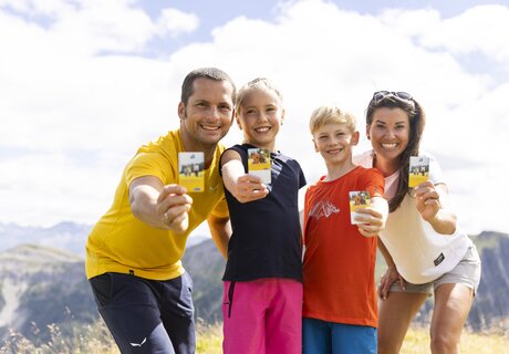 Eine glückliche Familie posiert im Freien mit Karten in der Hand.