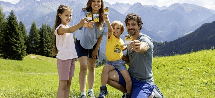 Family proudly holding snacks against a mountain backdrop.