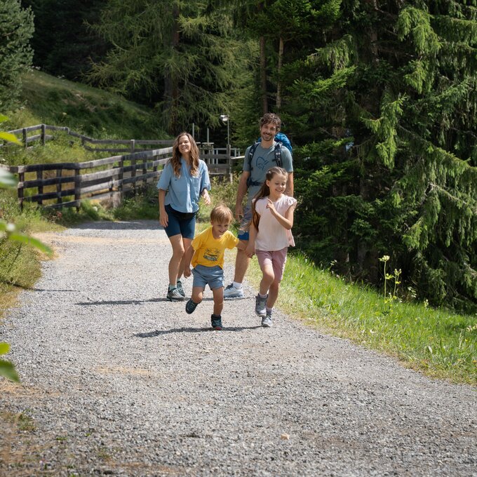 Eine Familie mit Kindern wandert fröhlich auf einem schottrigen Weg.
