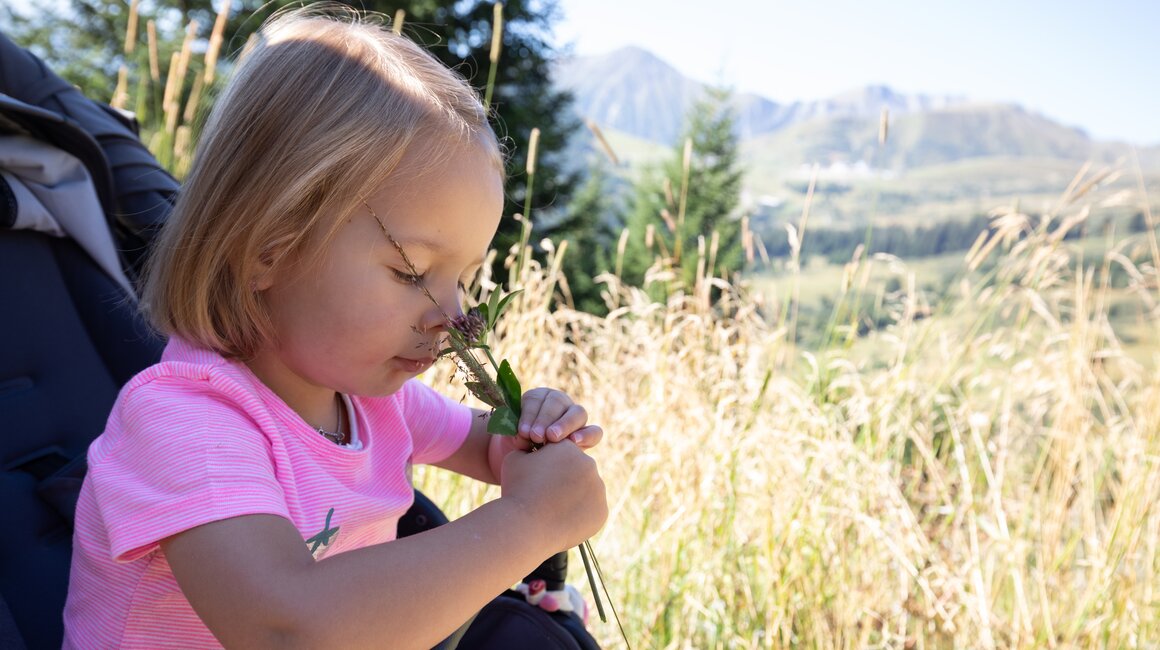 A child in nature smelling a flower.