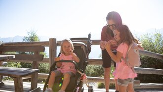 Two girls and a woman enjoying quality time outdoors in sunny weather.