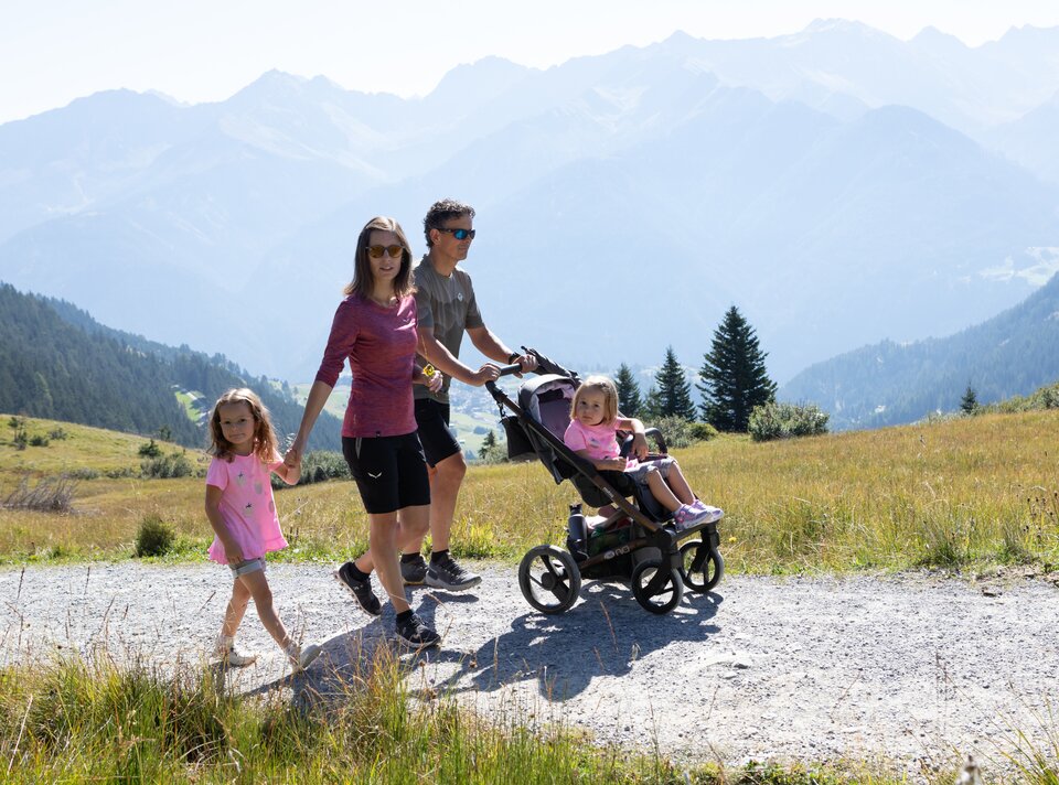 A family walks with a stroller in the mountains.