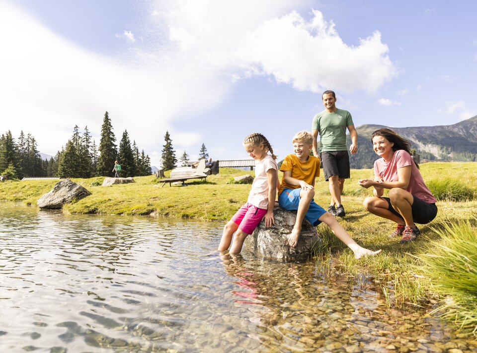 Four people enjoy a day by the lake, playing and smiling.