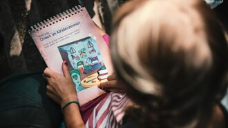 Een kind houdt een kleurboek met de titel 'Chaos in de Kinderkamer'.