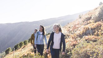 A family happily hiking in the mountains under sunny weather.