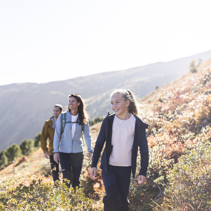 A family happily hiking in the mountains under sunny weather.