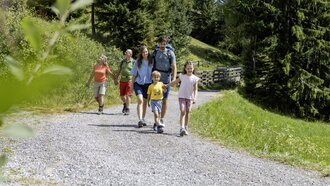 Eine Familie wandert auf einem Schotterweg in der Natur.