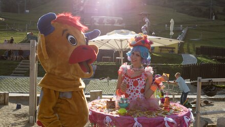 A clown and a mascot interact under the sunshine.