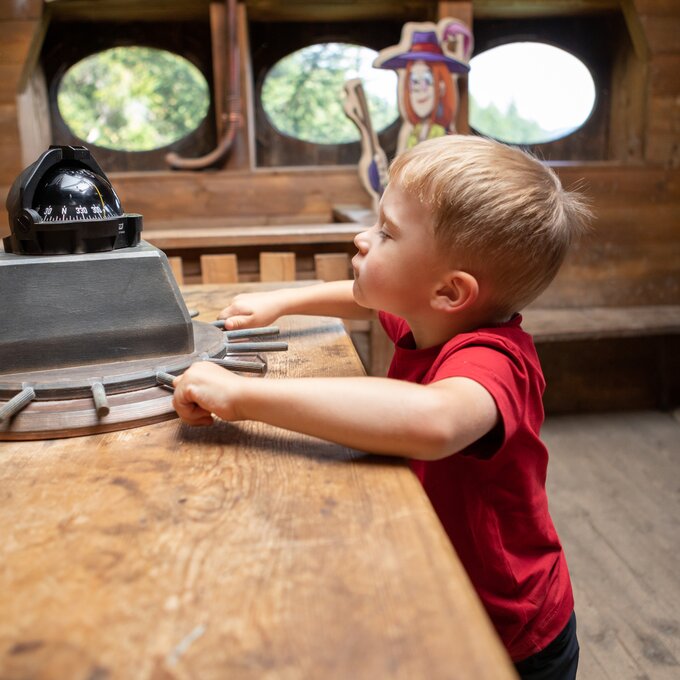 A boy explores the helm on a pirate ship.