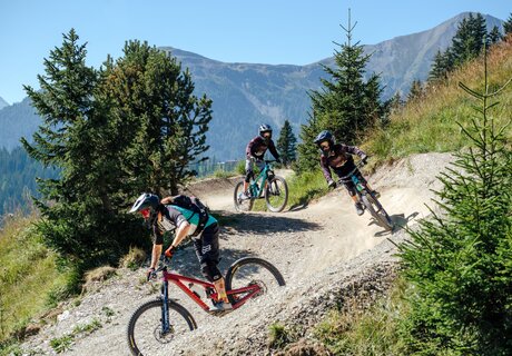 Three mountain bikers riding on a gravel trail in the Alps.