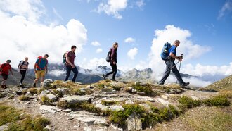 Menschen wandern in den Bergen unter blauem Himmel.