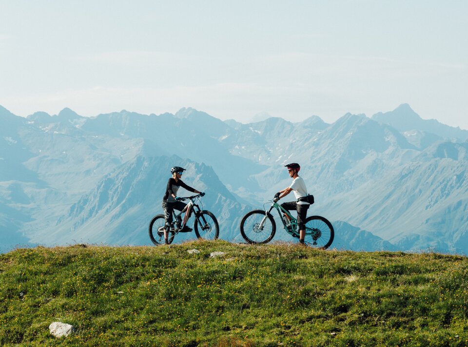 Zwei Radfahrer genießen die Aussicht in den Bergen.