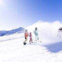 Eine Familie genießt das Skifahren unter klarem Himmel.