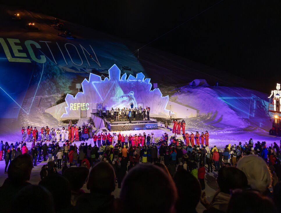 Menschenmenge bei einer nächtlichen Veranstaltung in den Bergen.