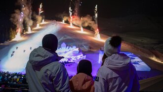 Family watching a spectacular firework display at night in the mountains.