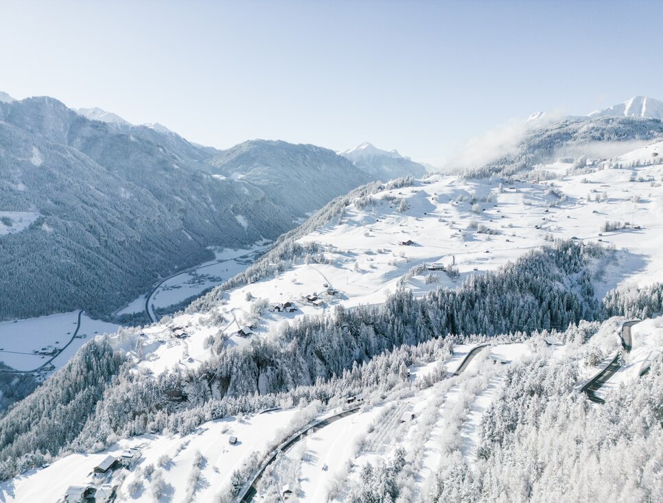 Luchtfoto van een besneeuwd Alpenlandschap met huisjes.