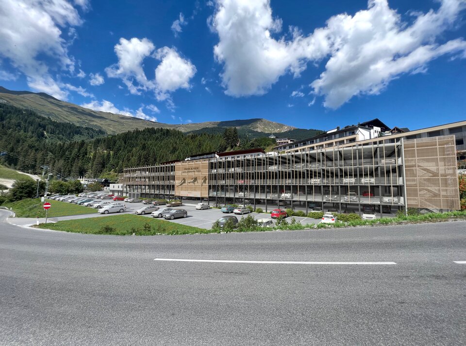 Een modern gebouw omringd door bergen en wolken.