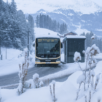 Bus hält an einer Haltestelle in einer verschneiten Landschaft.