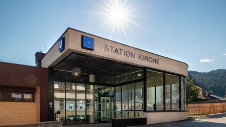 Modern subway station with glass front and clock in the Alps.