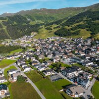 Blick auf ein malerisches Dorf in den Bergen mit grünen Wiesen.