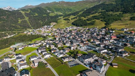Blick auf ein malerisches Dorf in den Bergen mit grünen Wiesen.