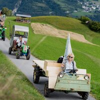 Eine Gruppe von Traktoren fährt auf einer Straße durch die Berge.
