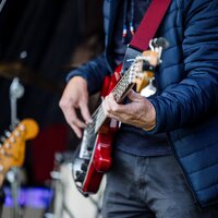 Ein Gitarrist spielt auf einer roten E-Gitarre auf einer Bühne.