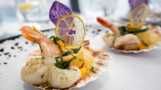 Ein elegantes Tellergericht mit Garnelen, Zucchini und Limonen.