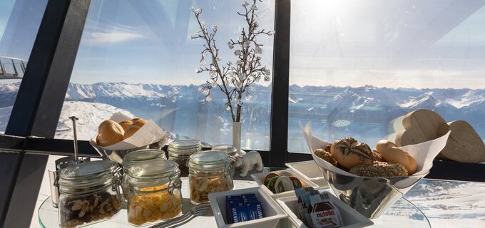 Ein Tisch mit diversen Snacks und Panorama-Blick auf die Berge.
