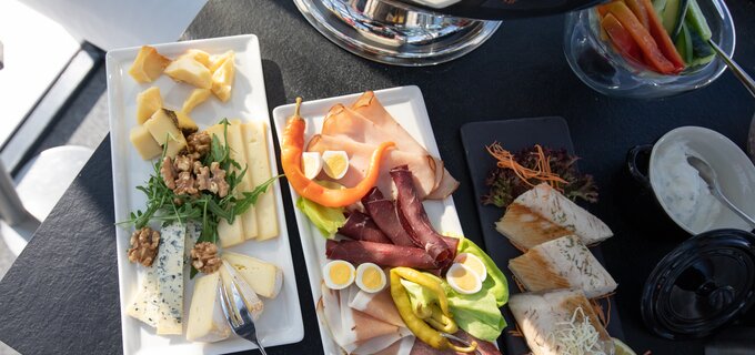 Eine Auswahl an Käse, Wurst und Gemüse auf einem Tisch.