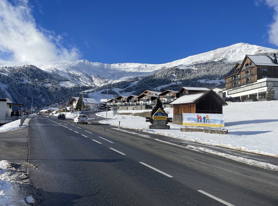 A village in the mountains with snow-covered homes and blue sky.