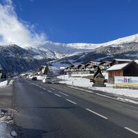 Ein Dorf in den Bergen mit schneebedeckten Häusern und blauen Himmel.