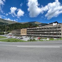 A modern building surrounded by mountains and clouds.